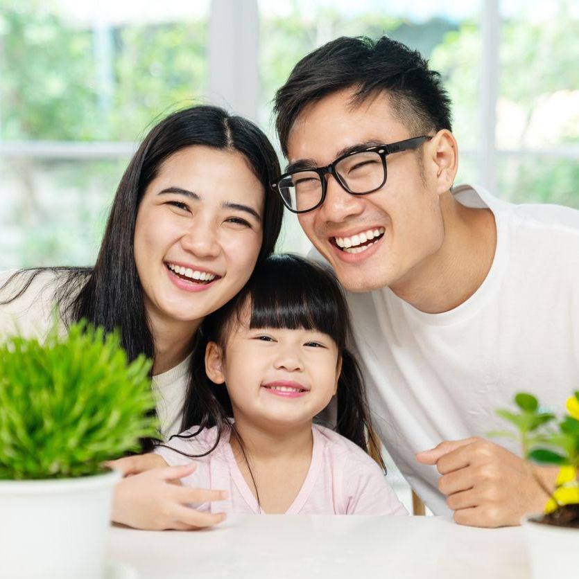 Portrait of young cute asian family three people at home smiling.