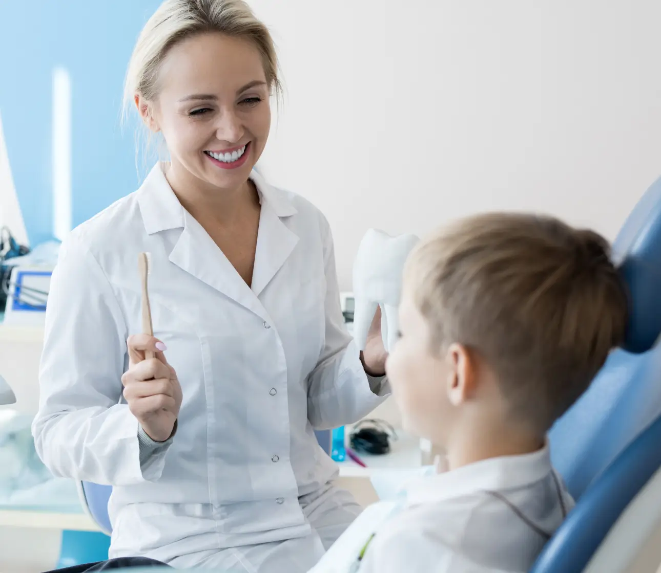 Smiling dentist explaining dental care to a child